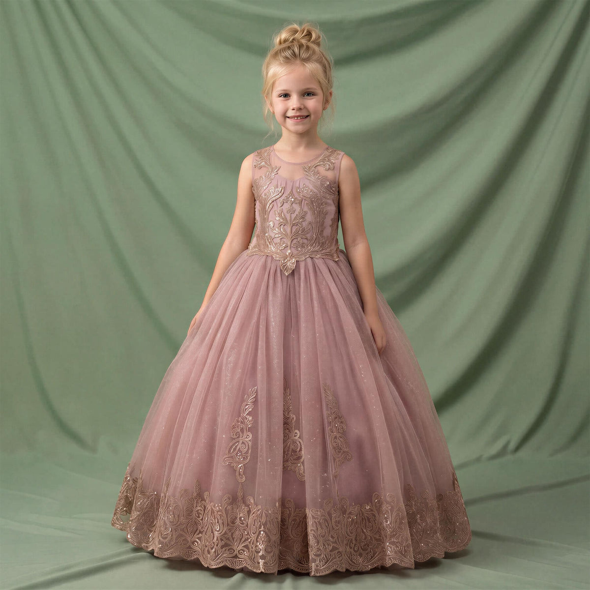 A young girl with blonde hair in a bun stands wearing a sleeveless dusty pink ball gown with gold floral embroidery and a tulle skirt, posed against a draped sage green backdrop. Main image