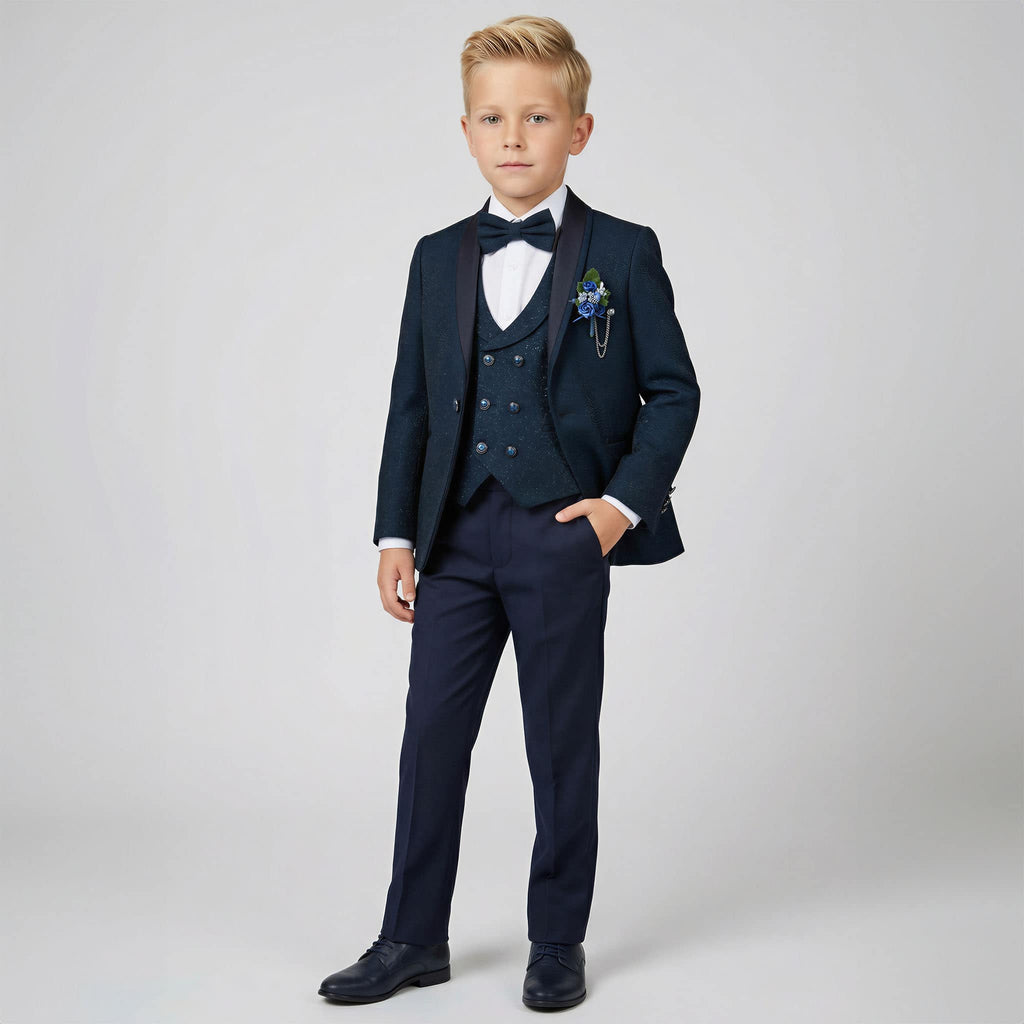 A young boy modeling a navy blue three-piece formal suit with a white shirt, black bow tie, and a matching navy blazer and trousers, set against a plain light gray studio background.