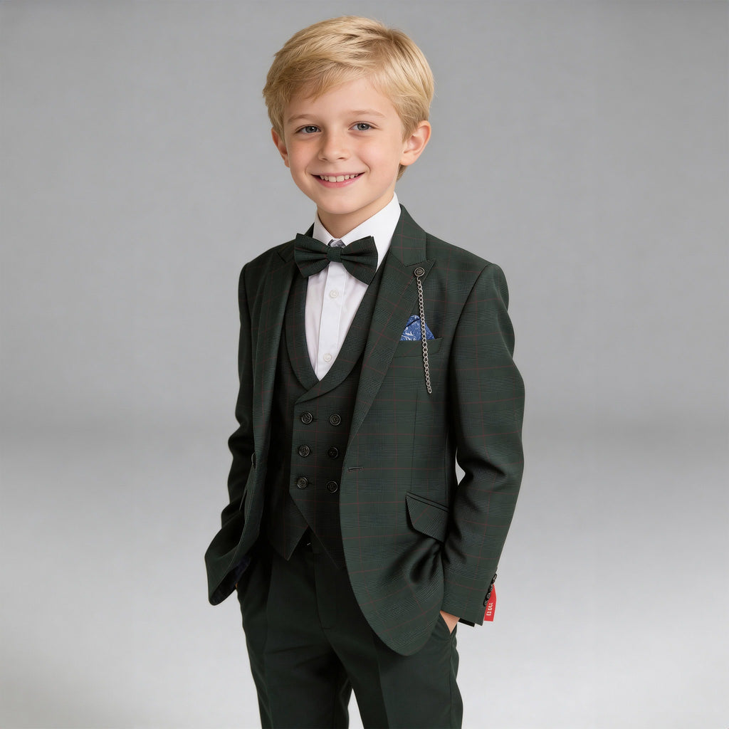 A young blond boy modeling a dark green three-piece suit with a subtle plaid pattern, featuring a matching vest, trousers, black bow tie, and a blue patterned pocket square, set against a solid gray studio background.